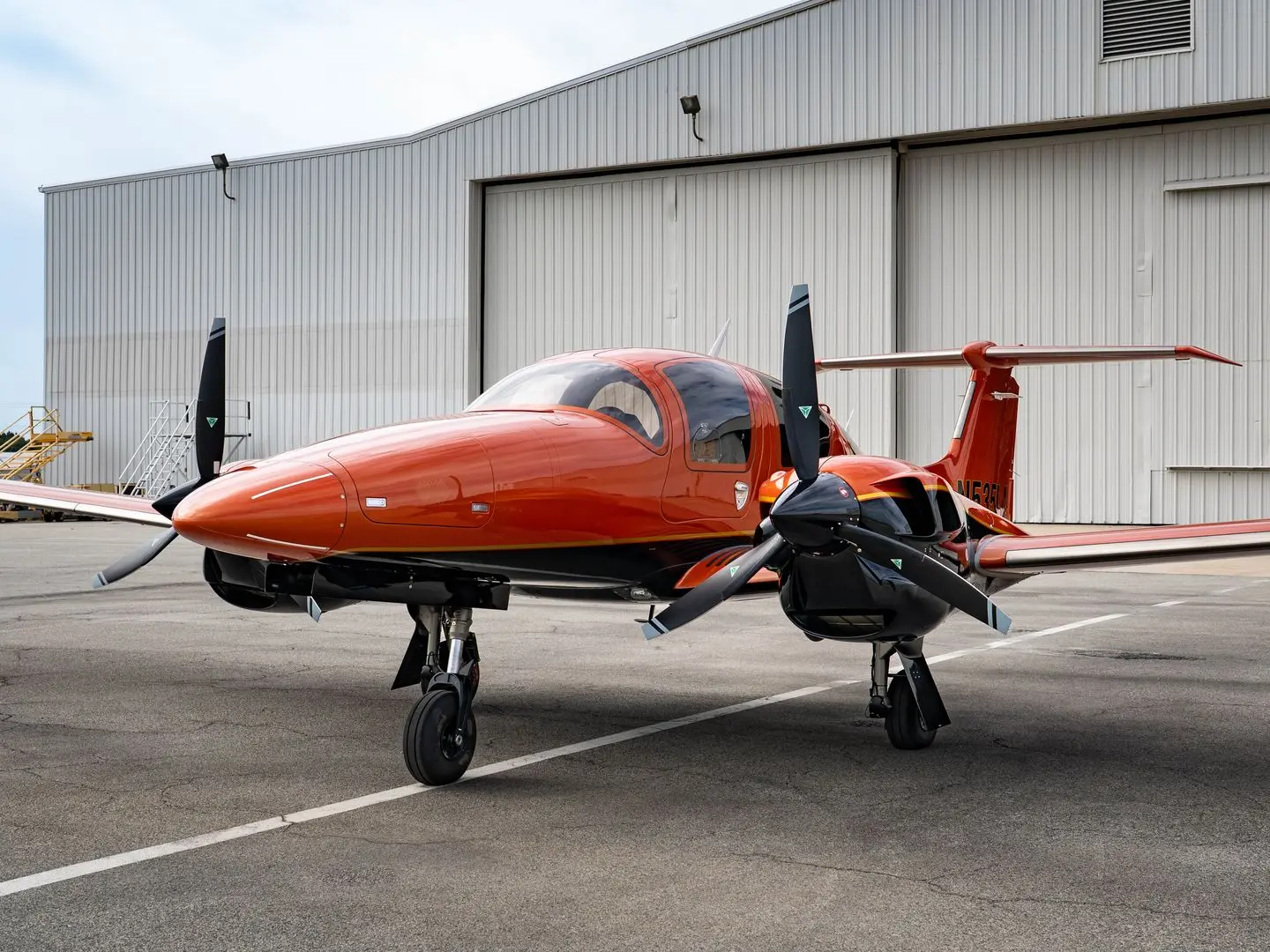 Diamond DA62 twin-engine aircraft in premium orange and black exterior parked on the ramp, showcasing its modern design, propellers, and spacious 7-seat cabin.